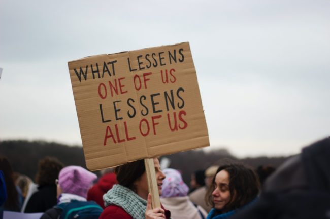 Protest sign: what lessens one of us lessens all of us