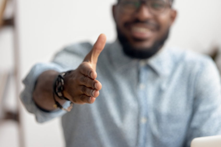 Creating a better hiring experience represented by hiring manager extending handshake, welcoming a new hire