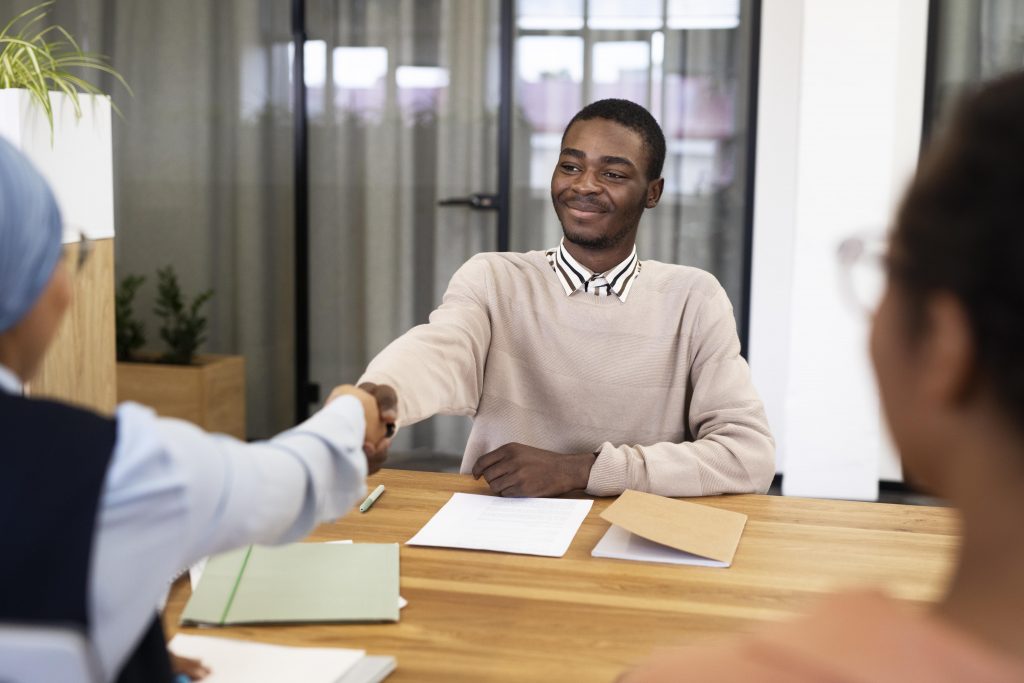 Working with recruiters, a young man shakes hands with recruiter following success in a job interview.
